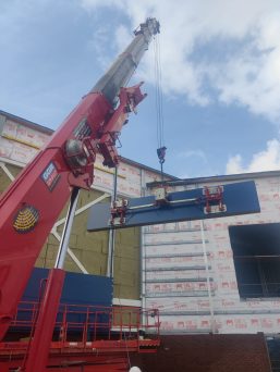 GGR Group's UNIC URW-706 Mini Spider Crane with searcher hook and Flexi-Clad VCL12 cladding lifter installing cladding.