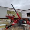 GGR Group's UNIC URW-706 Mini Spider Crane with searcher hook and Flexi-Clad VCL12 cladding lifter installing cladding.
