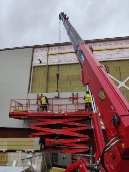 GGR Group's UNIC URW-706 Mini Spider Crane with searcher hook and Flexi-Clad VCL12 cladding lifter installing cladding.