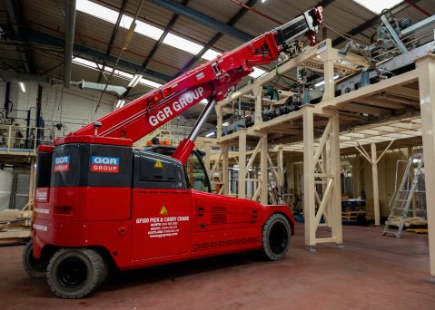 The GF180 Pick and Carry Crane lifting loads inside a bottling and packaging plant.