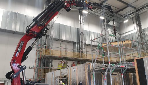 GGR Group's TMC 525 Articulated Spider Crane lifting prefabricated internal walls for a house inside the University of Salford's Eco House 2.0