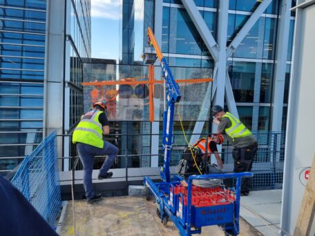 MFC750 Floor Crane & P11104 Glass Vacuum Lifter lifting glass on a rooftop.
